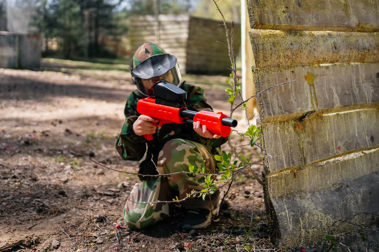 Ребенок целится в противника на игре в детский пейнтбол