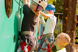Инструктор помогает ребёнку пройти верёвочную трассу